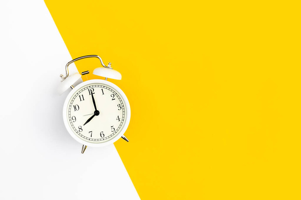 White alarm clock on a white and yellow background, flat lay, copy space. - Photo, Image