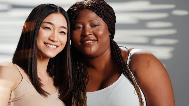 Interracial girls embracing and expressing self confidence, doing skincare and advertisement in studio. Happy women posing and showing self acceptance, body positivity femininity concept. - Photo, Image