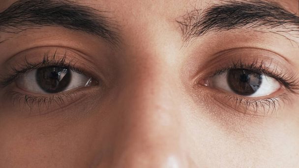 Human eyes. Vision correction ophthalmology. Closeup of male face with sad pensive look brown color iris dark eyelashes eyebrows. - 写真・画像