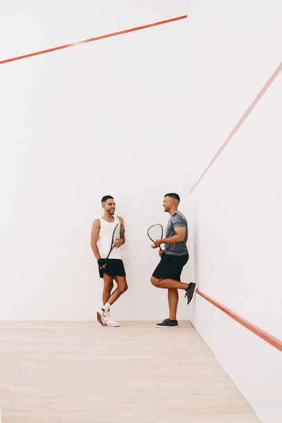Czas na zabawę i czas na spotkania towarzyskie. dwóch młodych mężczyzn na czacie po grze w squasha - Zdjęcie, obraz