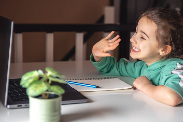 Смешная девочка перед экраном ноутбука, концепция онлайн-обучения, домашняя школа. - Фото, изображение