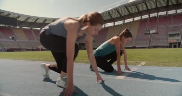 Three young people preparing to race each other at the race track on a stadium - Footage, Video