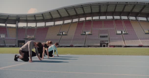 Three young people compete on the running track at an empty stadium - Footage, Video