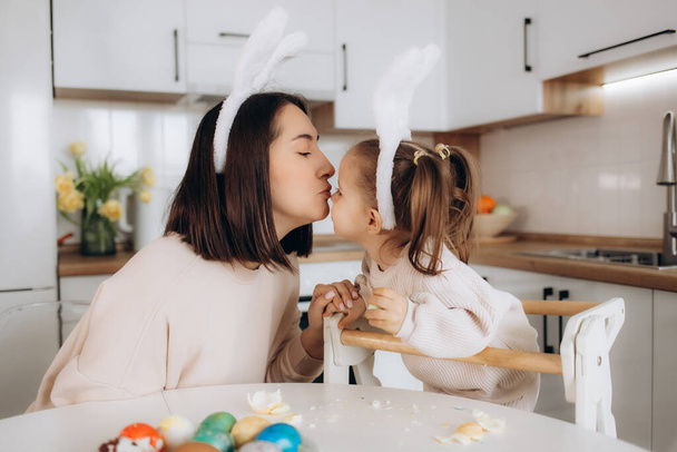 feliz familia madre e hijo niña pinta huevos para Pascua en casa
 - Foto, imagen