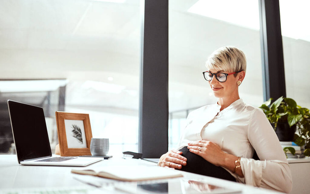 Jongler sa carrière et sa grossesse avec une facilité absolue. une femme d'affaires enceinte assise à un bureau dans un bureau - Photo, image