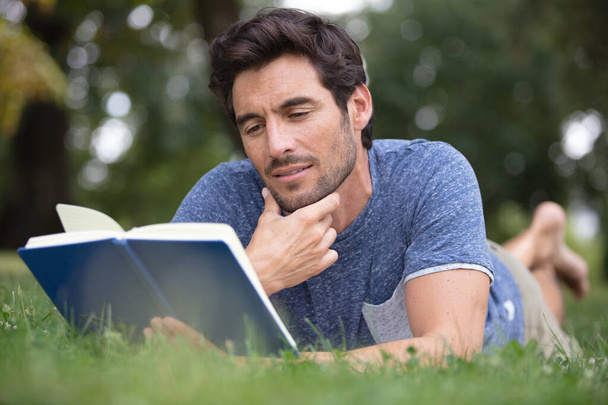 young man reading a book outside in the park - Foto, immagini