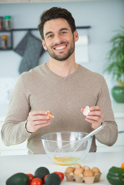 man breaking eggs into a bowl - Photo, image