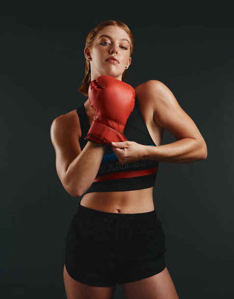 I challenge you. Studio portrait of a sporty young woman wearing boxing gloves against a black background - Foto, immagini