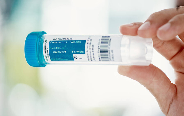 Hoffnung in der Flasche. Ein Wissenschaftler hält einen Behälter mit Coronavirus-Impfstoff darauf - Foto, Bild