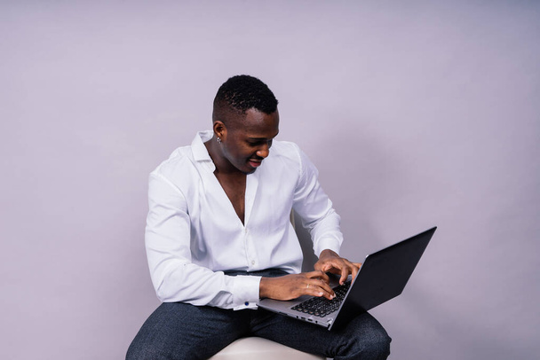 Optimistic african-american male student in a casual shirt using laptop pc isolated - Foto, Bild