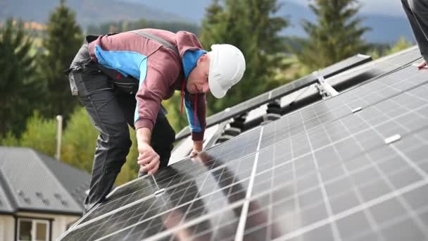 Man technicus montage fotovoltaïsche zonnepanelen op dak van huis. Ingenieur in helm installeren van zonnemodules met behulp van hex key. Begrip "alternatieve, hernieuwbare energie". - Video