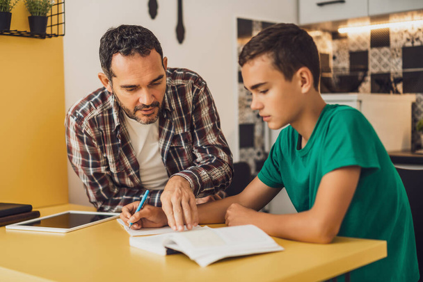 Vater hilft seinem Sohn beim Lernen. Sie machen gemeinsam Hausaufgaben. - Foto, Bild