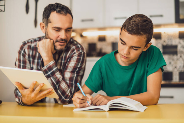 Père aide son fils à apprendre. Ils font leurs devoirs ensemble.. - Photo, image