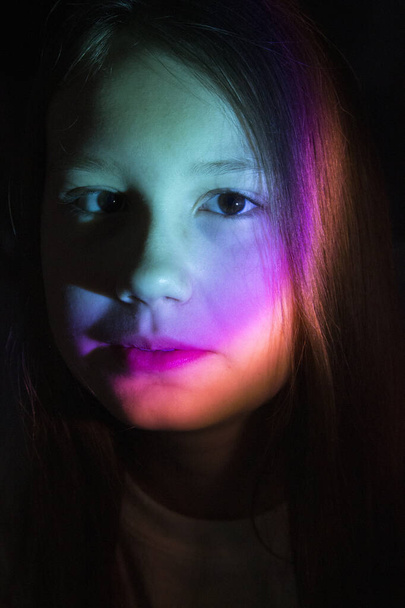 Retrato de una joven adolescente en luz de neón de color. La luz del arco iris cae sobre la cara de la chica. Retrato inusual de la fiesta. - Foto, Imagen