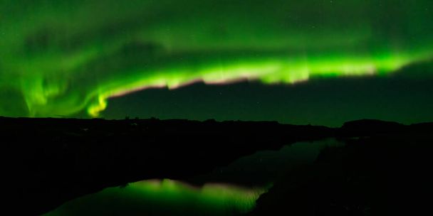 Espectacular aurora boreal rayos verdes y púrpura sobre el lago - Foto, imagen