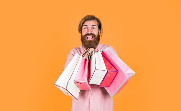 In shopping store. best sale offer. happy bearded man with present pack. cheerful brutal hipster hold gift. paper shopping bag. birthday surprise at party. man with package. prepare for holidays. - 写真・画像