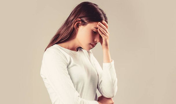 Brünette Frau berührt ihre Schläfen fühlen Stress, auf grauem Hintergrund. Frau mit starken Kopfschmerzen hält Hände auf dem Kopf. - Foto, Bild