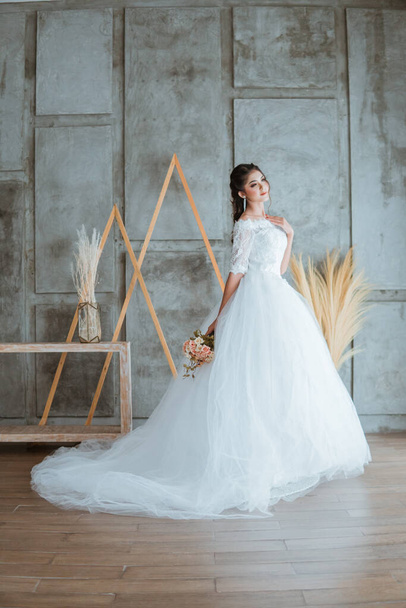 asiático novia en blanco largo rabo vestido de pie poner su mano izquierda en su pecho y llevar el ramo de flores - Foto, imagen