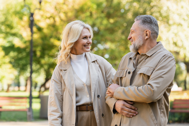 Happy blonde woman looking at husband while spending time in park  - Photo, Image