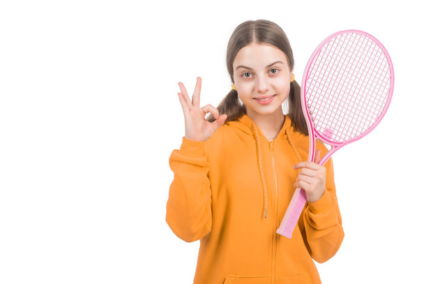 cheerful girl child hold tennis or badminton racket and show ok gesture isolated on white with copy space, healthy childhood. - Foto, Imagen