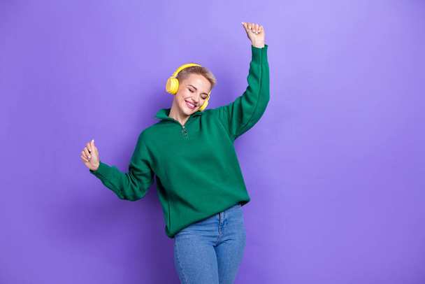 Photo of pretty lucky woman dressed green pullover rising fists dancing enjoying songs isolated purple color background. - 写真・画像