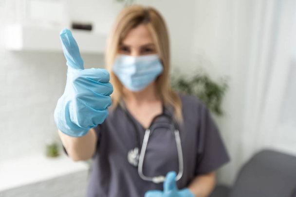 жінки-лікарі руки в нітрилових синіх рукавичках показують палець
. - Фото, зображення
