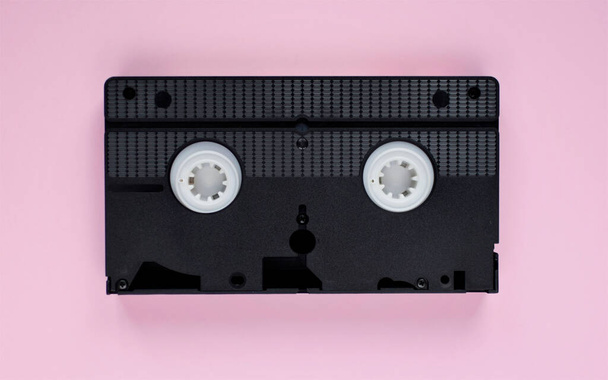 Pembe arka planda siyah VHS kasetin üst görüntüsü. Video kaset düzleştirildi - Fotoğraf, Görsel
