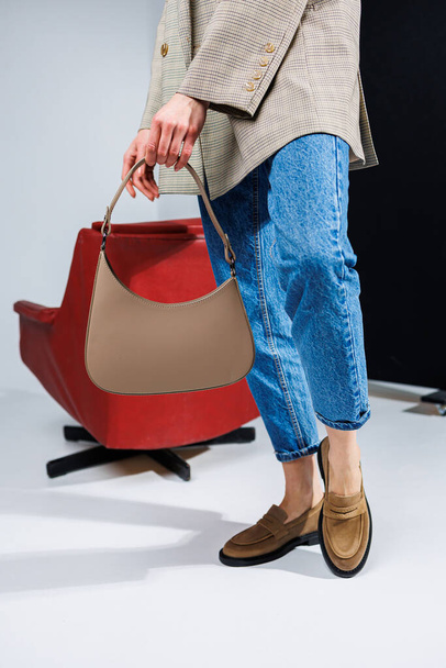 Women's leather stylish bag. Beige classic everyday bag in women's hands. - 写真・画像