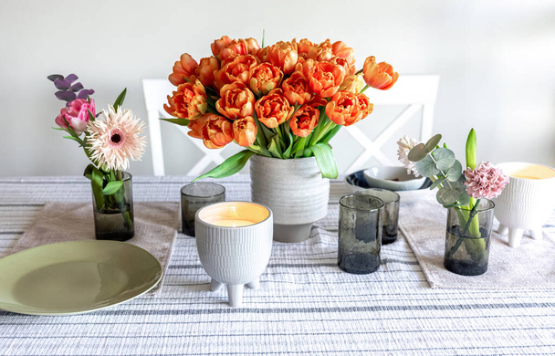 A bouquet of tulips, other flowers and a candle on the table, the concept of serving and decor, a cozy home. - Valokuva, kuva