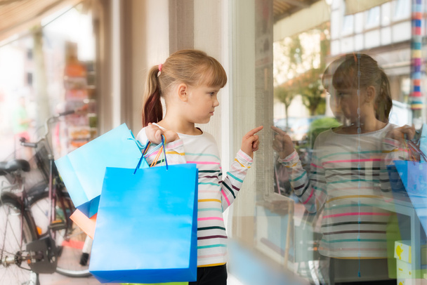 Mała dziewczynka patrząc na sklepowej  - Zdjęcie, obraz