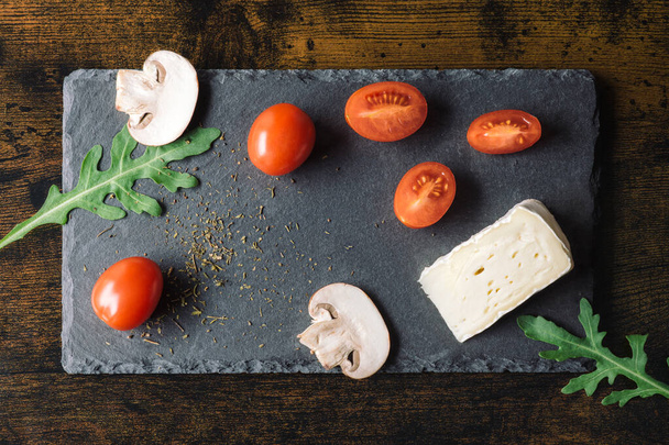 Třešňová rajčata se sýrem a rukolou na černém přírodním stánku v detailní scéně. Kvalitní fotografie - Fotografie, Obrázek