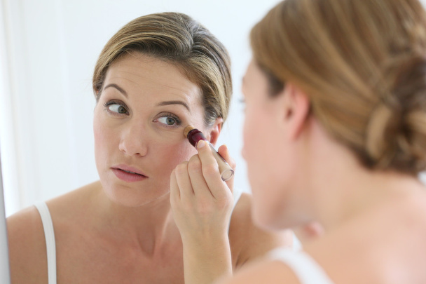 Woman applying concealer around eyes - Foto, immagini