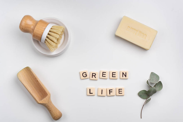 koncepcja zrównoważonego stylu życia płaska leżała z bambusową szczotką, drewnianą miarką, mydłem i zielonymi liśćmi. Zielone życie napisane literami płytek  - Zdjęcie, obraz