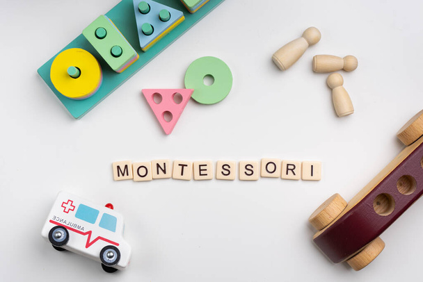 Montessori-Wort mit Buchstaben auf weißem Hintergrund mit Spielzeug - Foto, Bild