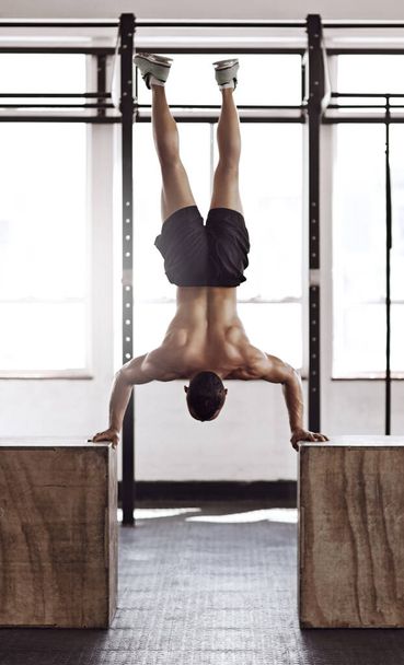 Budowanie jego ciała poprzez równowagę. Zdjęcie z tyłu młodego mężczyzny ćwiczącego na siłowni. - Zdjęcie, obraz