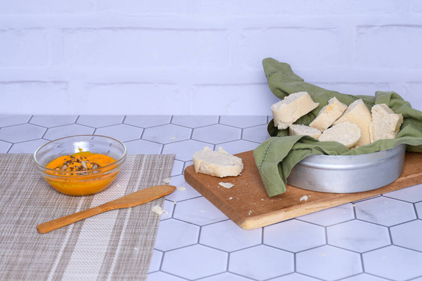 Glass container with homemade carrot mayonnaise, bread and spreader. - Photo, Image