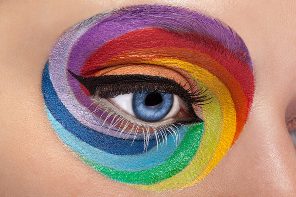 Primer plano ojo azul con el arco iris artístico maquillaje. Colores y colorido. ¡Joy! Maquillaje artístico y de moda. Inventar la adicción. Cosméticos. En el escenario conforman
 - Foto, Imagen