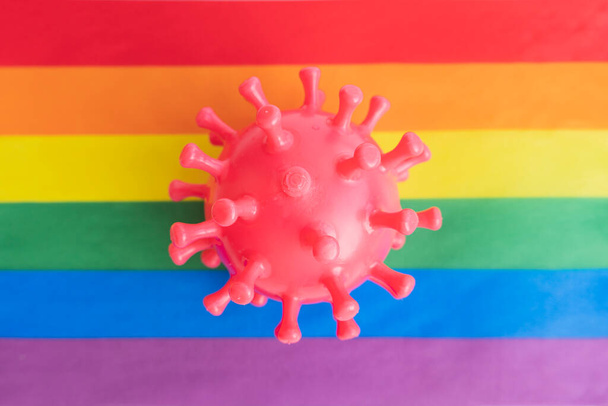 ゴム製のウイルスは虹の旗の上にある。ウイルスに感染する危険性の概念 - 写真・画像