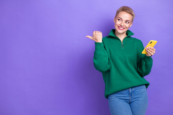 Photo of satisfied lovely girl blonde short hair phone browse direct finger mockup best online crypto exchange isolated on violet color background. - Фото, изображение