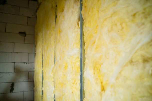 The partition is filled with glass wool. Frame wall from a metal profile with mineral wool close-up. Freshly built interior partition in a private house - 写真・画像