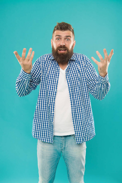confused bearded man in casual checkered shirt on blue background, embarrassment. - Foto, immagini