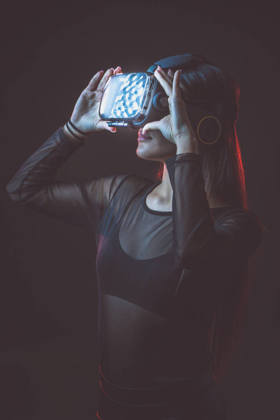 Beautiful active young attractive caucasian fit model woman uses hi tech futuristic Vr glassess for augmented reality. Photo of sportive beauty brunette sportswoman attractive white model. - Photo, Image