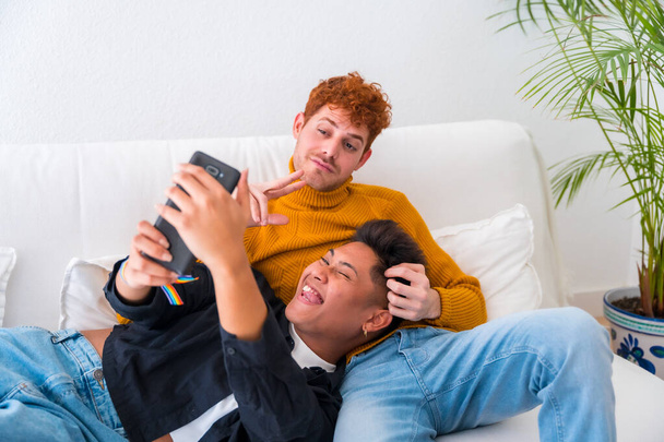 Beautiful gay couple being romantic indoors at home on the sofa, gay couple - Fotó, kép