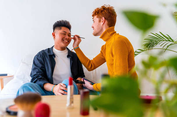 Beautiful gay couple putting on makeup and having fun being romantic indoors at home, lgbt concept - Foto, Imagem