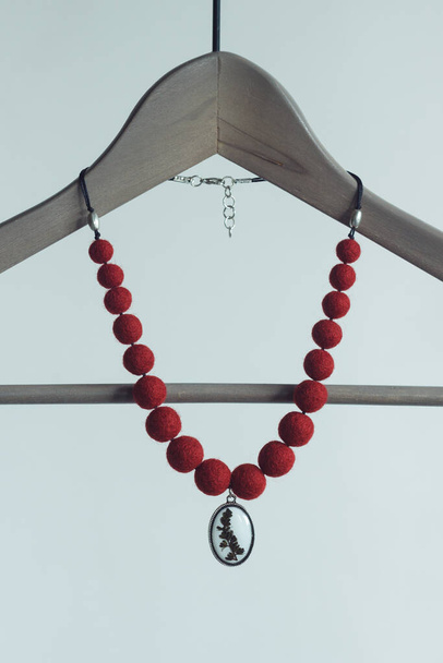 Rote Halskette mit Anhänger auf weißem Hintergrund. Halskette aus gefilzter Wolle - Foto, Bild
