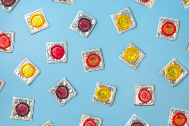 Top view Kolorowe prezerwatywy w opakowaniu na niebieskim tle. - Zdjęcie, obraz