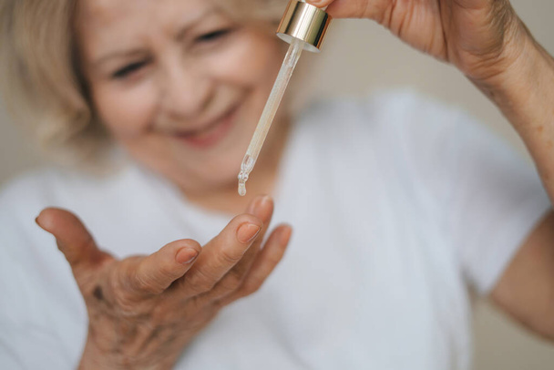 Close-up portrait person applying a drop of skin care liquid from pipette on her fingers. Skin care. Positive person. Facial beauty. Anti-aging cosmetic - Foto, Bild