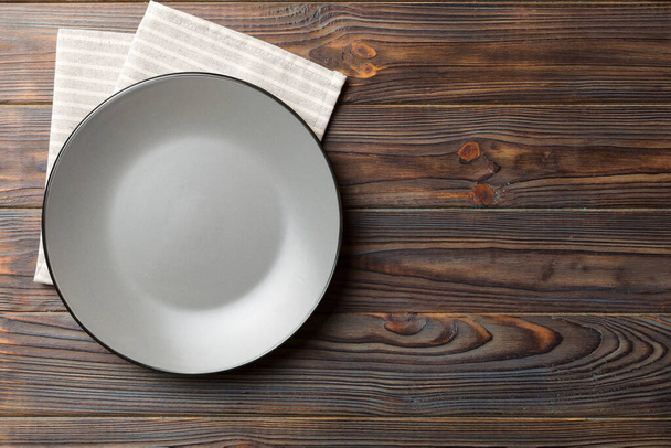 Bovenaanzicht op gekleurde achtergrond lege ronde grijze plaat op tafelkleed voor voedsel. Lege schotel op servet met ruimte voor uw ontwerp. - Foto, afbeelding