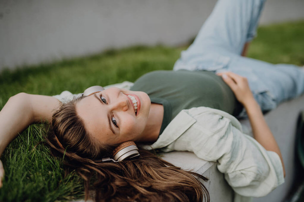 Young woman resting in a city, enjoying the music trough headphones. - Fotografie, Obrázek
