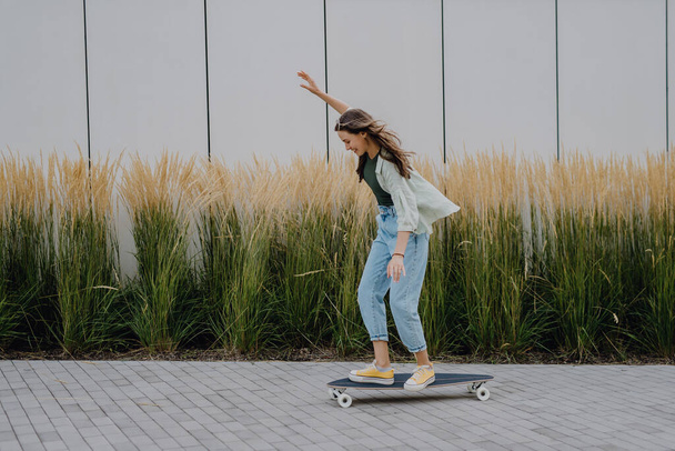 Young woman ridding a skateboard in a city. Youth culture and commuting concept. - Фото, зображення